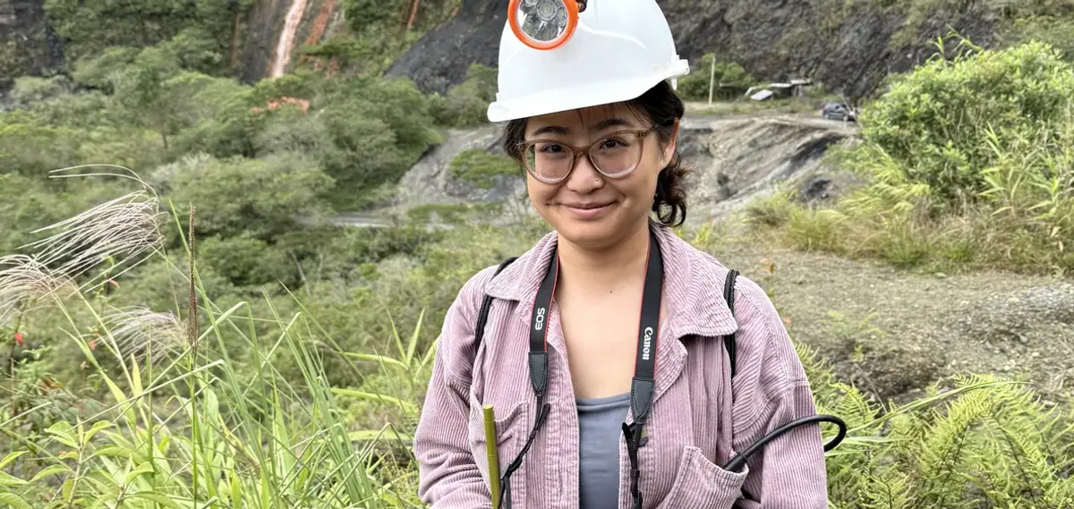 Traveler with a camera and mining helmet in a green valley in Chivor