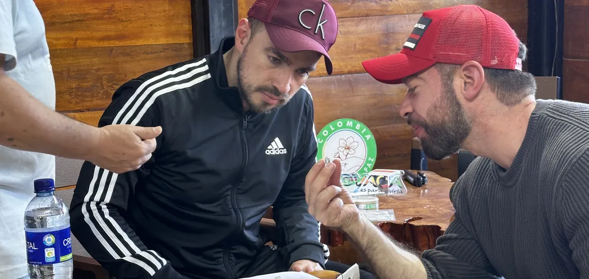 Two travelers examining a raw emerald at a table